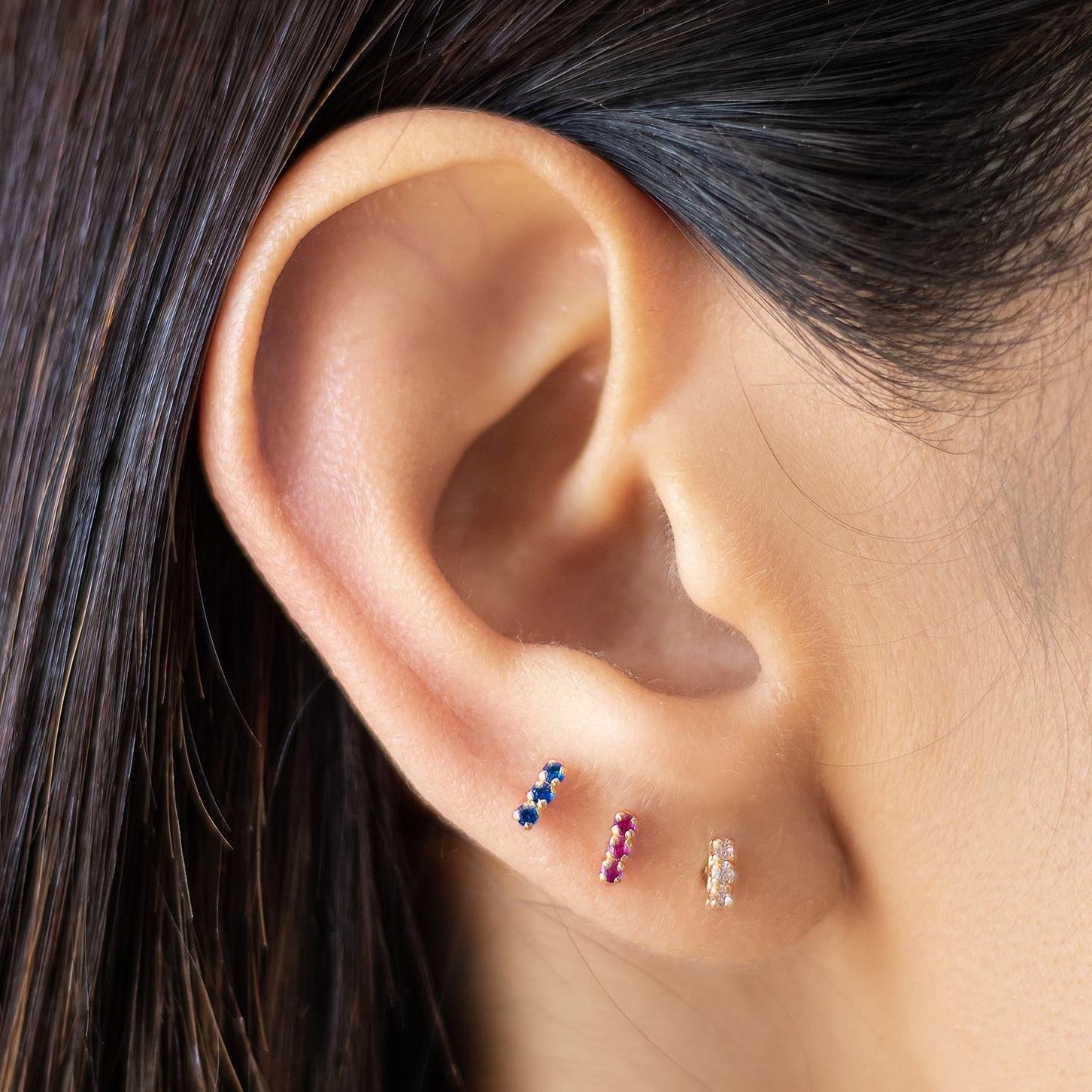 10K gold bar stud earrings in white, red, and blue stones shown on lobe piercings – dainty screw back earrings for lobe, helix, and cartilage
